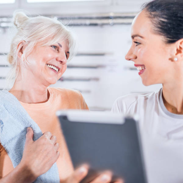 Physiothérapeute discutant avec cliente penchée sur tablette